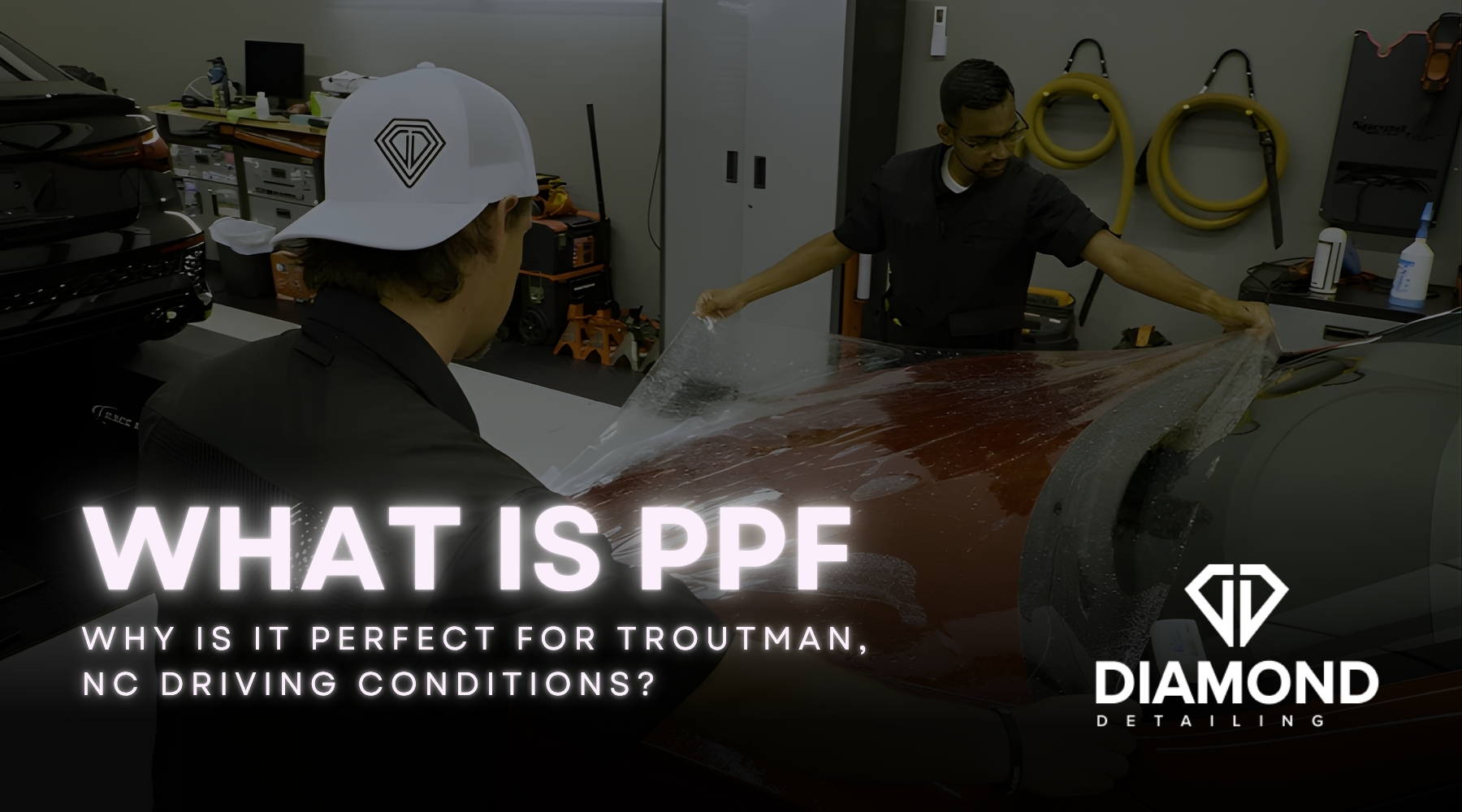Two auto detailing technicians apply a clear Paint Protection Film to the hood of a red vehicle inside a professional garage. This visual demonstrates the practical answer to the question What Is PPF by showing its application process.