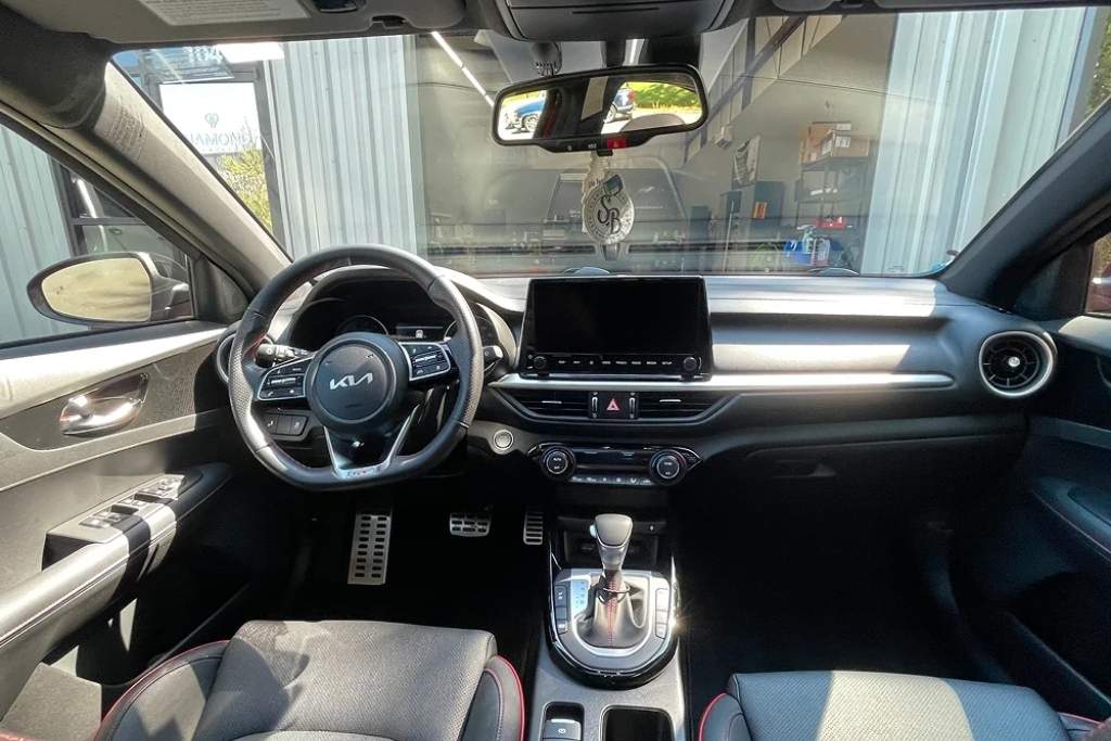 Interior view of a Kia parked at Diamond Detailing in Troutman, NC, with visible sunlight casting across the dashboard and seats, highlighting the Key Benefits of Window Tinting such as UV protection, heat rejection, and glare reduction.