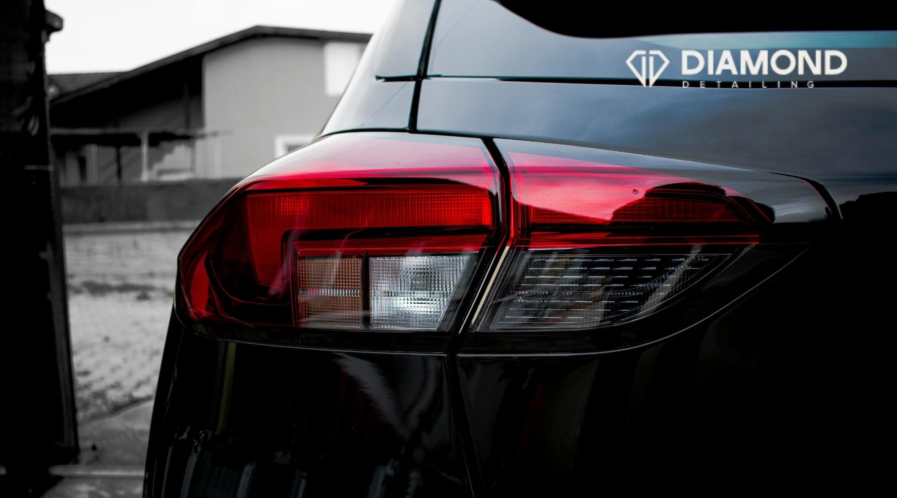 Close-up of a polished black vehicle taillight with Diamond Detailing branding on the rear window