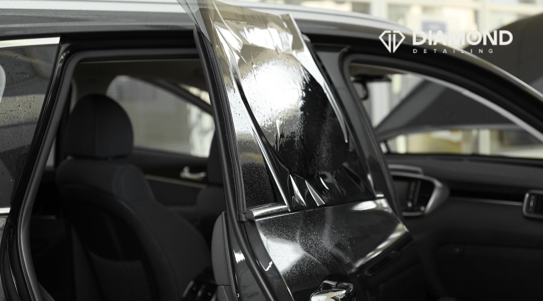 Professional car window tint installation on a vehicle door by Diamond Detailing