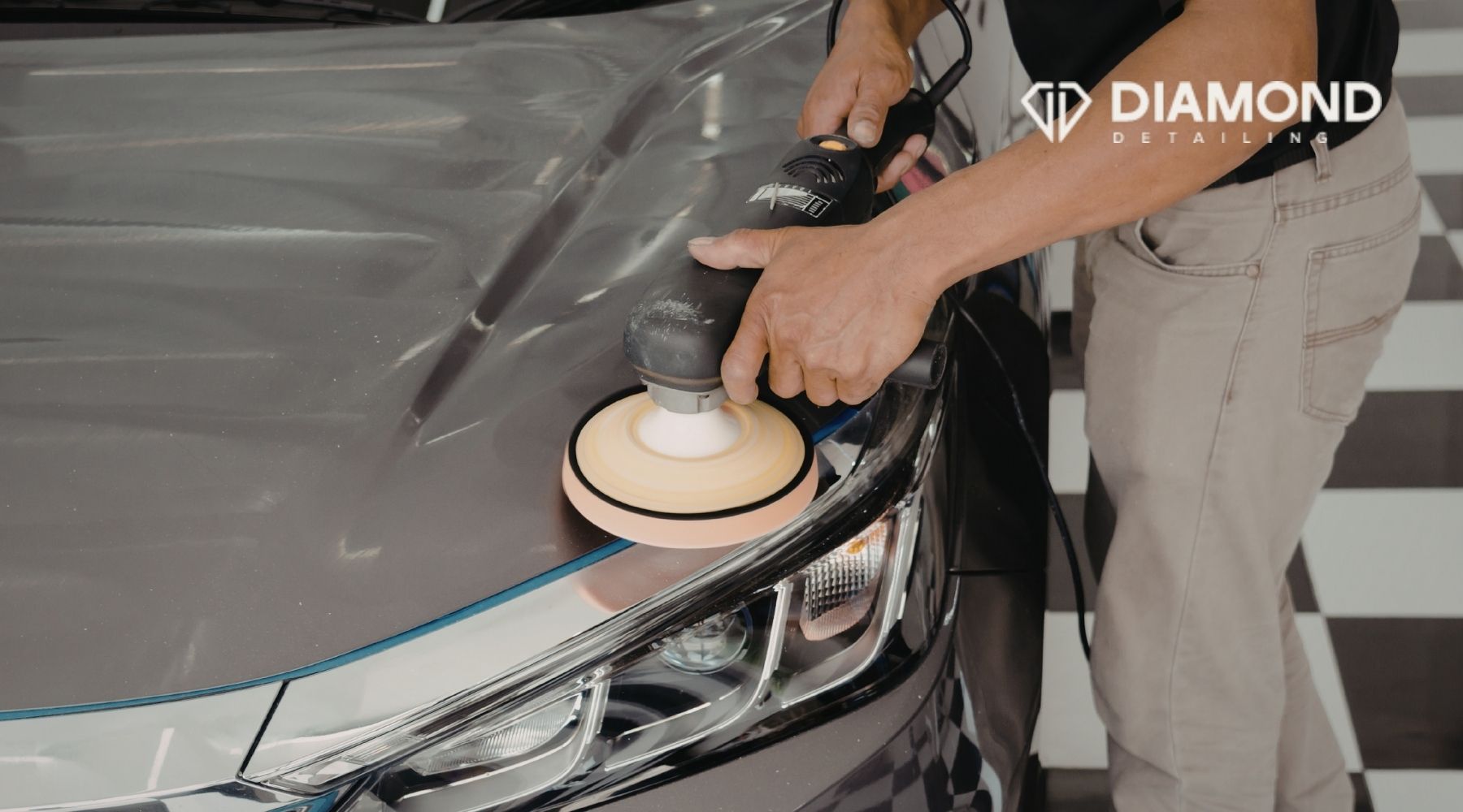 Technician polishing the hood of a gray car with a machine buffer at Diamond Detailing