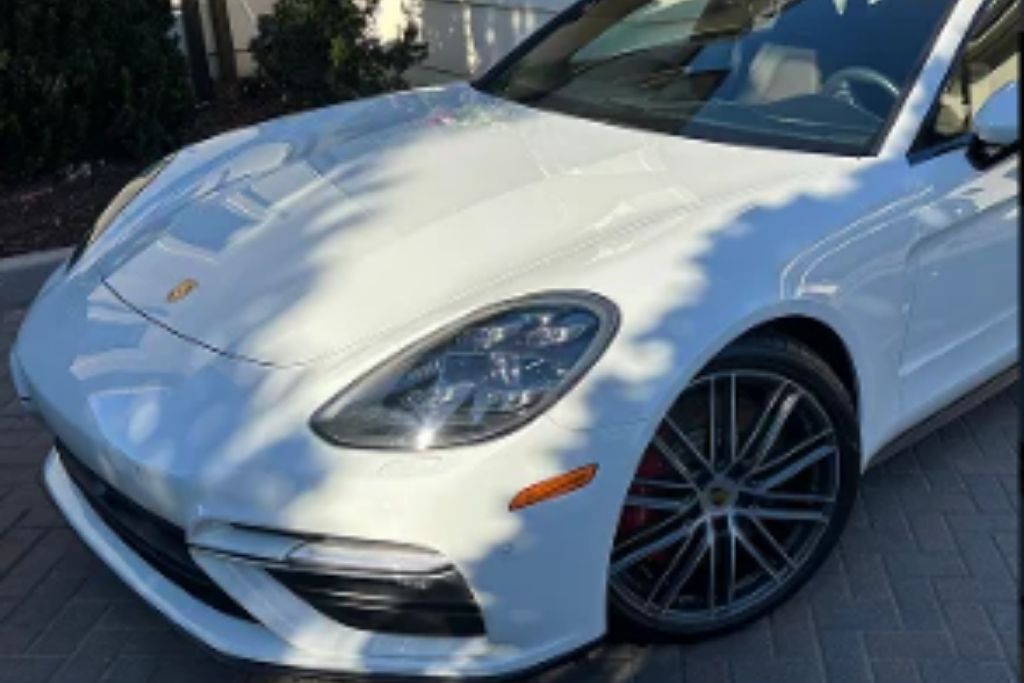 Front-side view of a white luxury sedan with a glossy finish parked outdoors after detailing