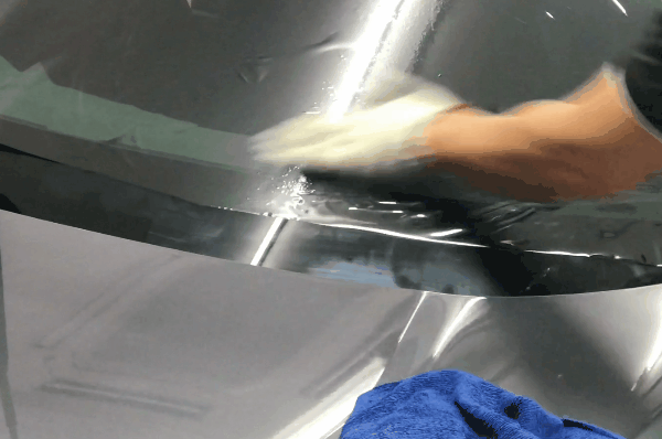 Technician smoothing automotive window tint film onto a car windshield during installation